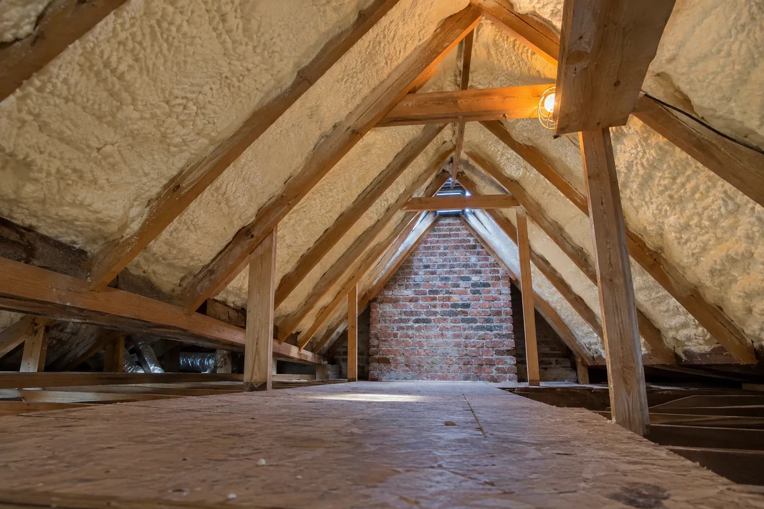 Illustration of a low residential attic with selected roof-bay insulation and visible brick gable