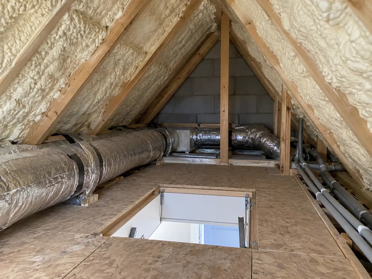 Illustration of attic hatch landing with cream insulated roof slopes and carefully protected service ducts