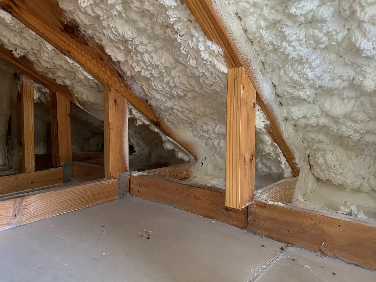 Illustration of low attic eave junction, white foam surrounding dry timber and a ceiling-top transition