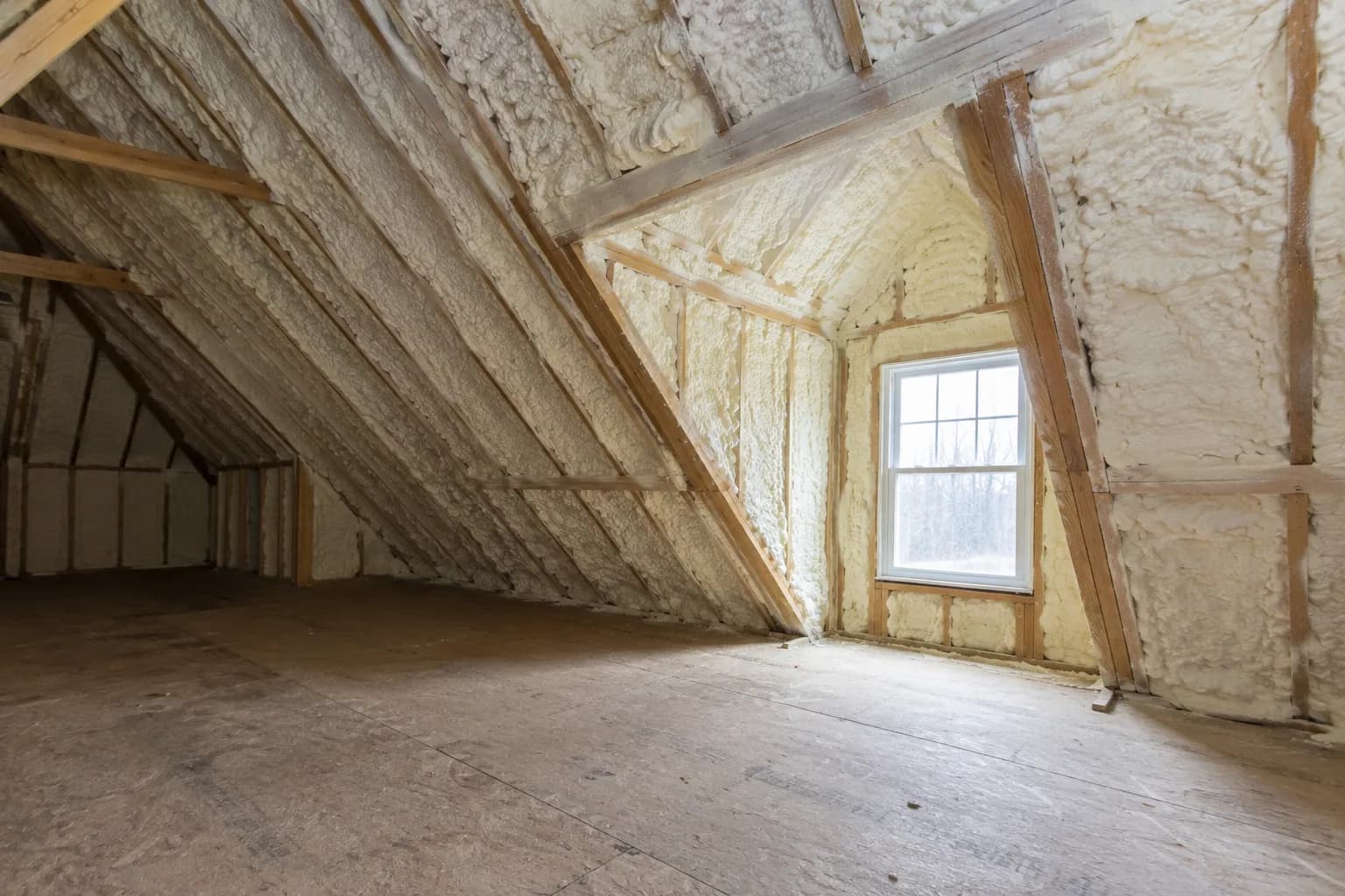 Illustration of existing house attic interior with cream-white foam, steep rafters and a small dormer junction, cloudy daylight