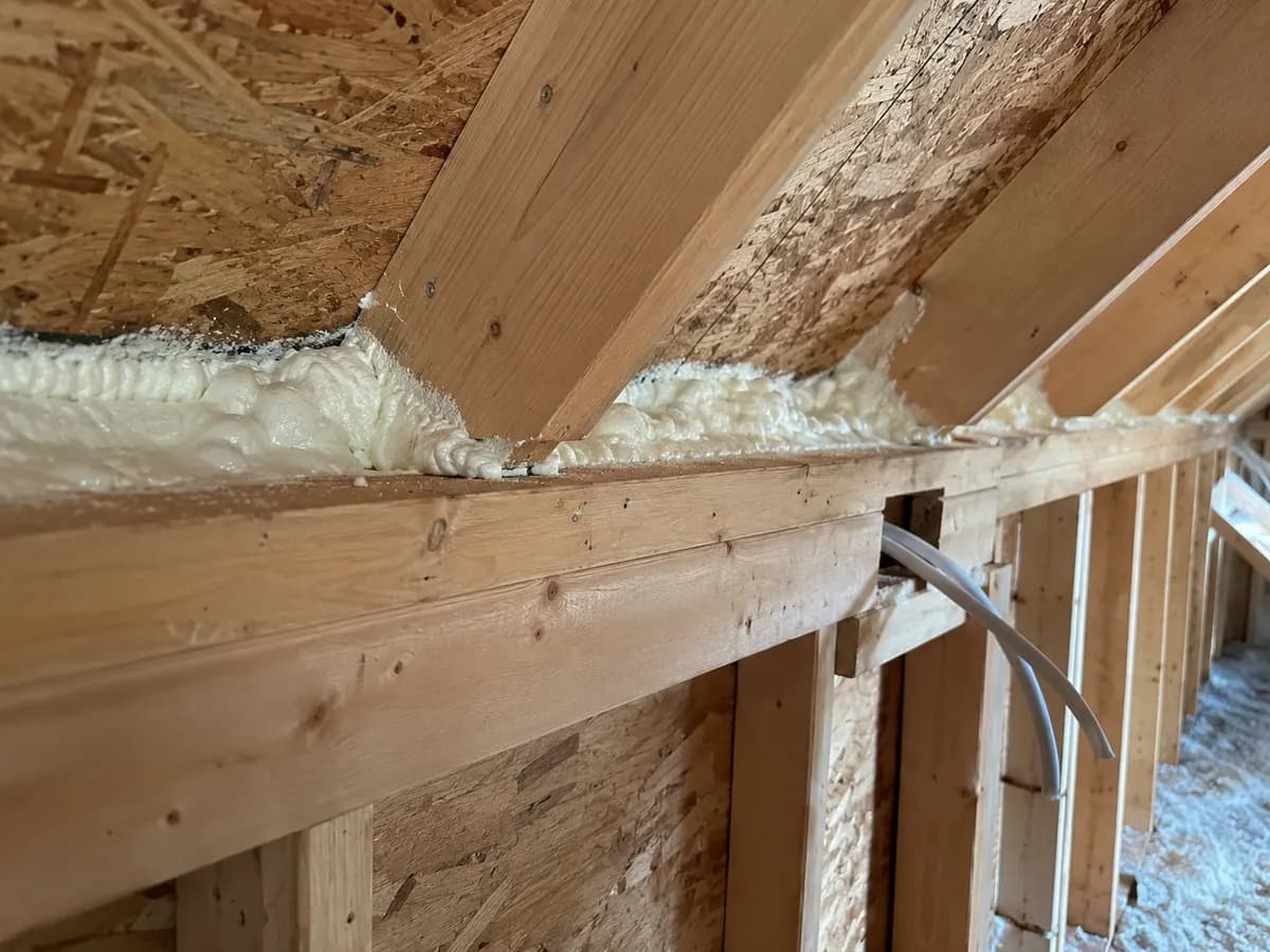 Illustration of close timber attic wall-top connection with white foam and an unblocked service opening