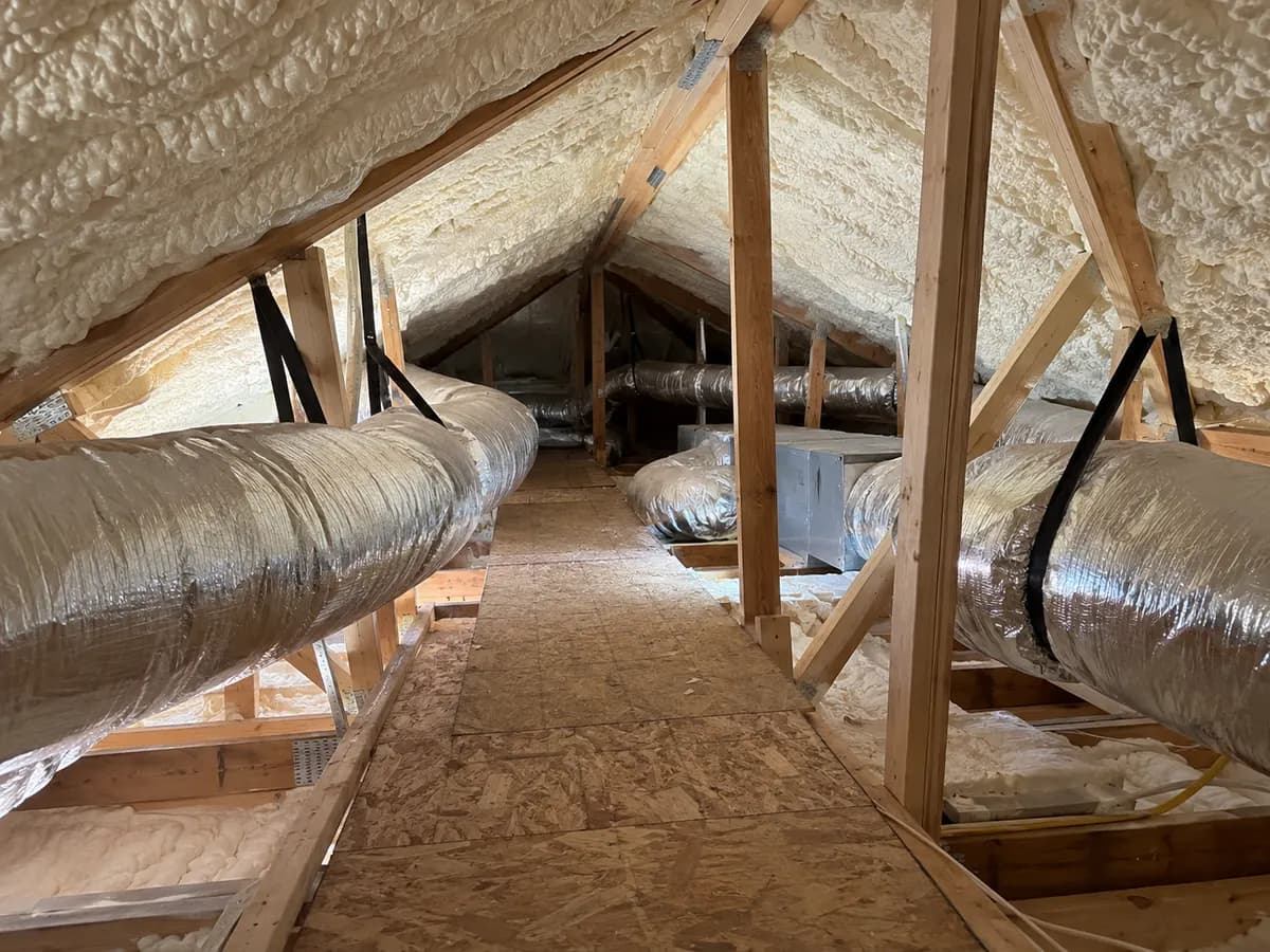 Illustration of attic service walkway beneath intersecting insulated roof planes and realistic protected ductwork