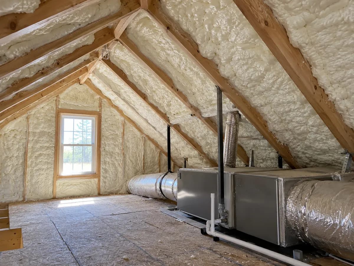 Illustration of attic roof intersection with white foam and visible equipment clearance, natural window light