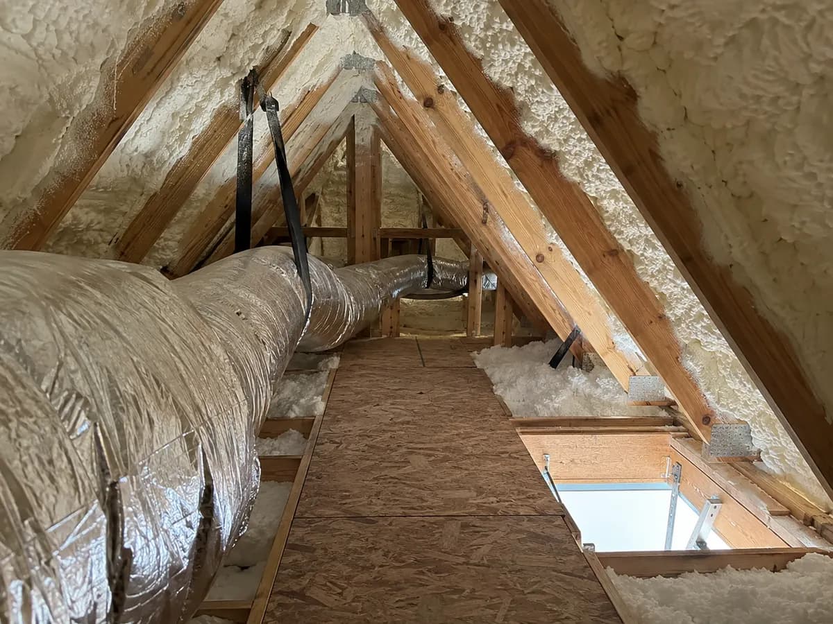 Illustration of attic maintenance walkway under insulated rafters with a masked service duct and clear hatch area