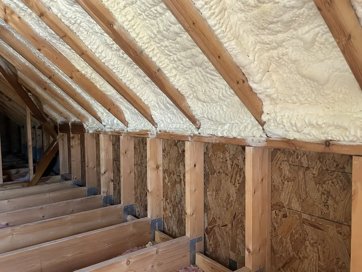 Illustration of attic roof-to-wall transition adjoining intact retained ceiling framing, realistic pale foam and wood