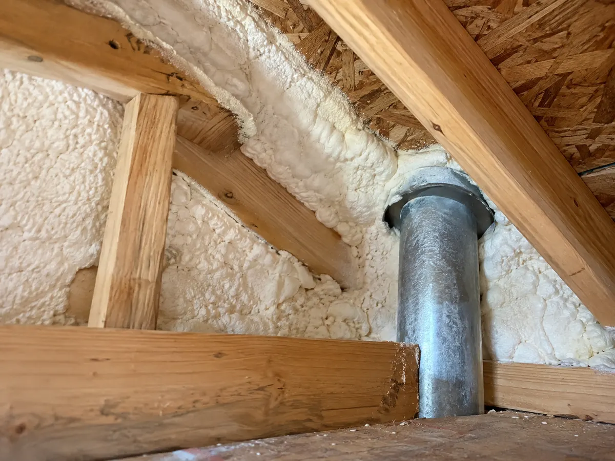 Illustration of close attic eave corner with white foam and intact framing around a service penetration