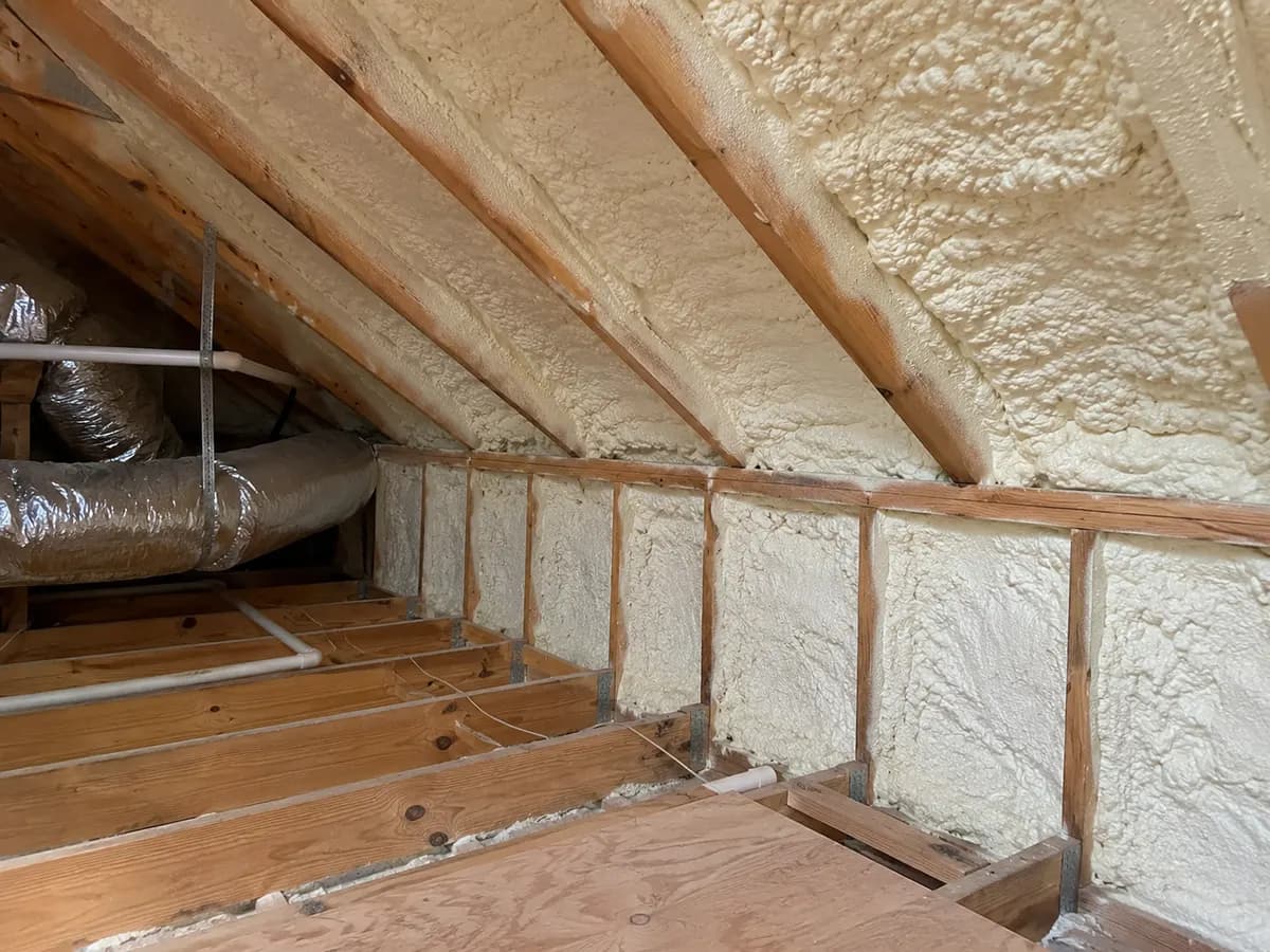 Illustration of attic roof intersection and knee wall insulated in cream foam with simple mechanical clearance